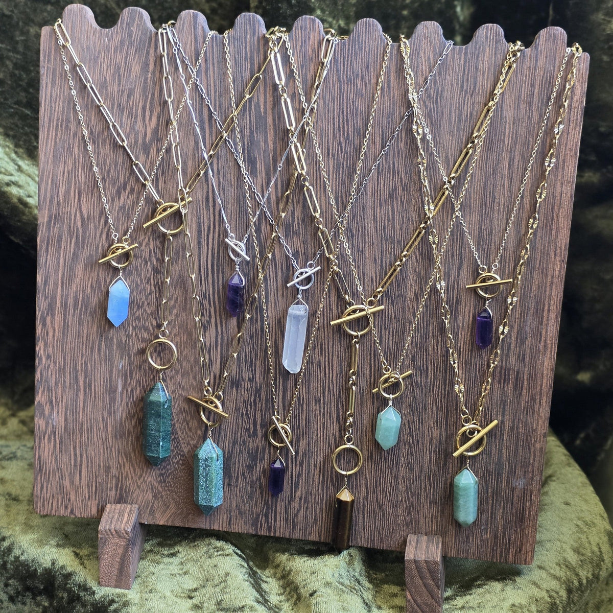 Stone The Raven handmade crystal pendulum necklaces on a wooden display